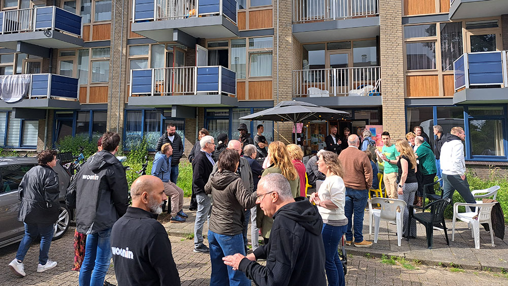 Groep mensen, stoelen en parasol voor een flat